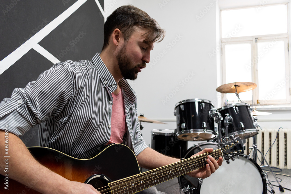 Fototapeta premium Male musician is playing music on wooden acoustic guitar, capture chords by finger.