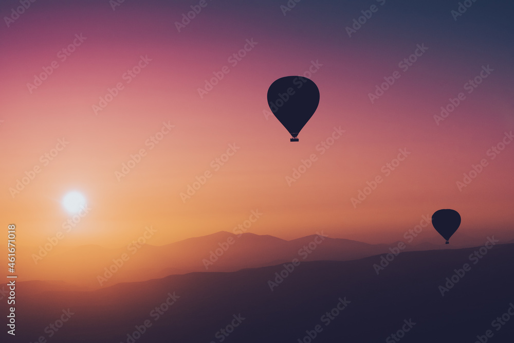 Naklejka premium hot air balloon silhouettes with sun rising over the mountains