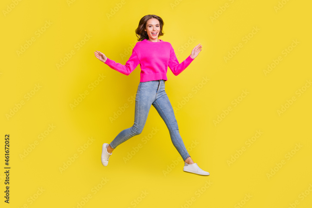 Full length photo of sweet adorable wavy young woman wear pink sweater jumping walking isolated yellow color background