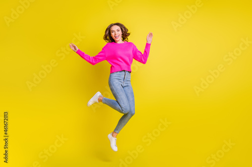 Full length photo of pretty charming curly young lady dressed pink pullover jumping high isolated yellow color background