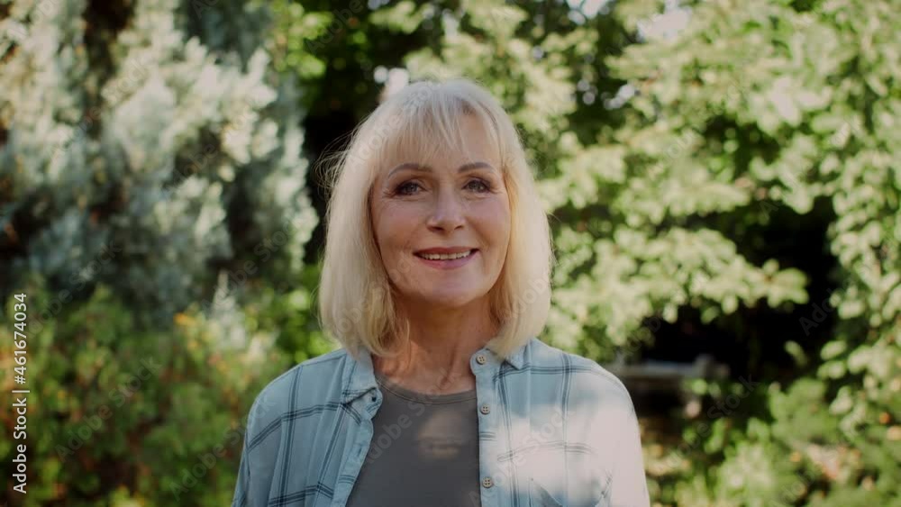 Beautiful Smiling Senior Woman Standing In Summer Garden And Looking At Camera, Beautiful Smiling Senior Woman Standing In Summer Garden And Looking At Camera,