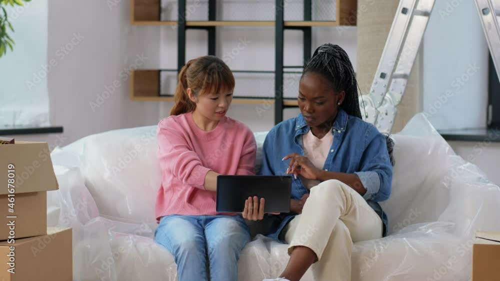 moving, people and real estate concept - happy smiling women with tablet pc computer and boxes talking and planning at new home moving, people and real estate concept - happy smiling women with tablet pc computer and boxes talking and planning at new home
