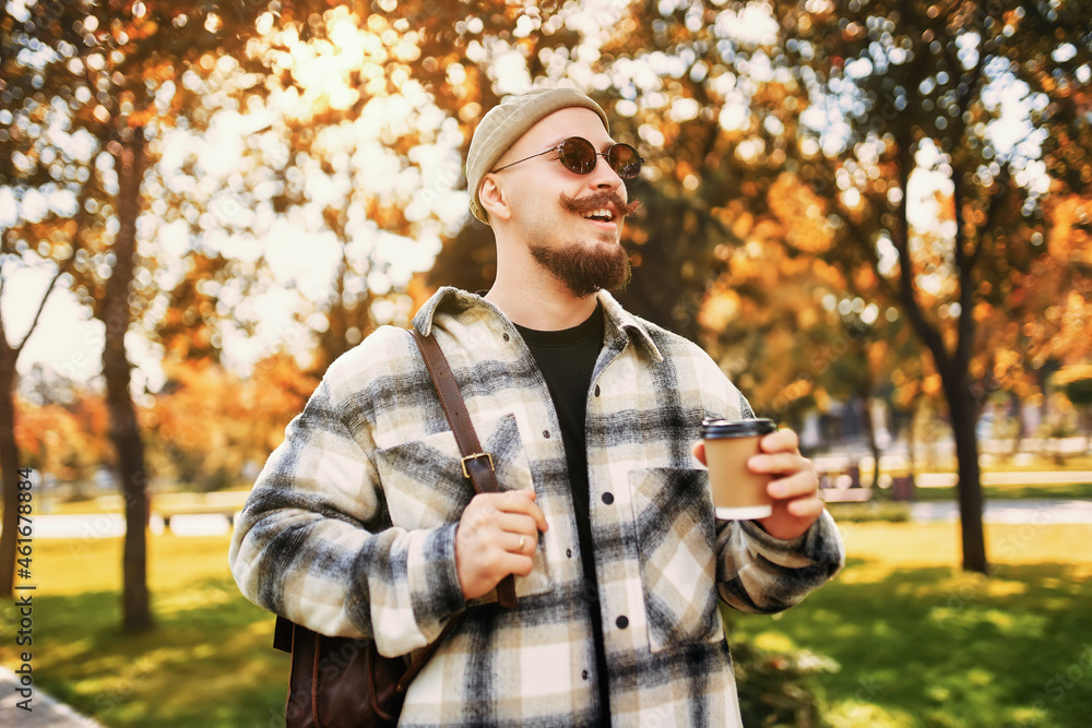 Handsome happy smiling bearded man drinks coffee outside the street while walks in the city park Handsome happy smiling bearded man drinks coffee outside the street while walks in the city park
