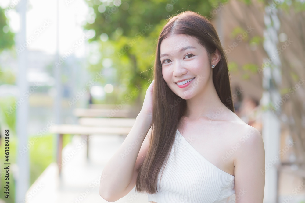 Asian beautiful woman with  good skin in cream shirt standing smiling happily on blurred background.