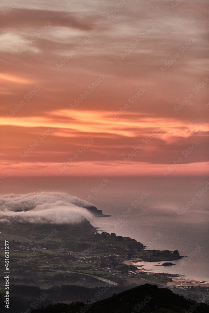 Clouds descend over Playa de la Isla at sunset. Asturias. Spain