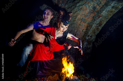 Halloween. Images of the dead vampires and witches. Man and woman vampires conjure near the fire.