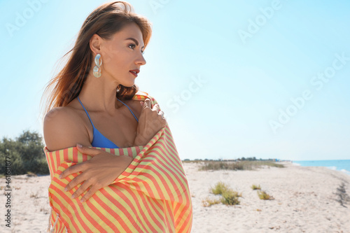 Beautiful woman with beach towel on sandy seashore