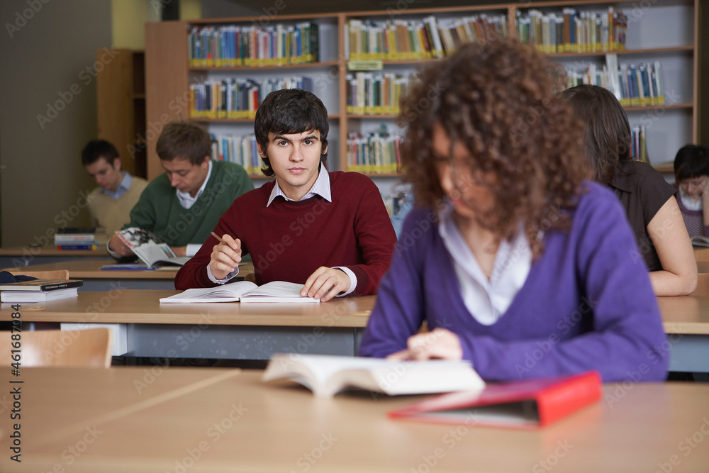 Students reading books at desks in library Students reading books at desks in library