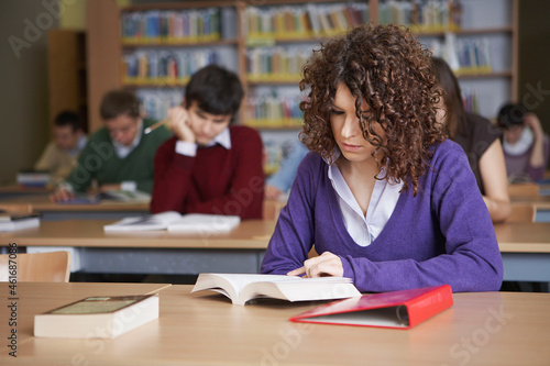 Students reading books at desks in library