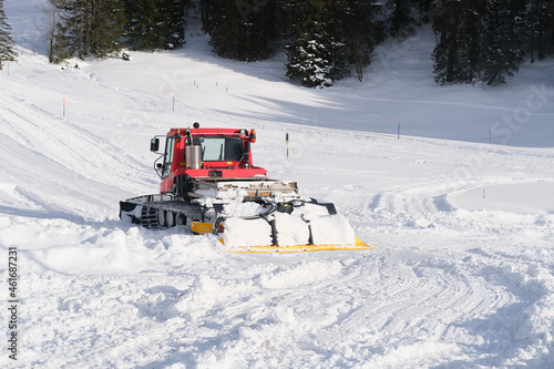 red tractor of municipal service in mountains of Swiss Alps with wide snow shovel clears the road from heavy snow, Winter Activity Concept, travel by car, problems of utilities in winter