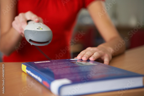 Close-up of students hands scanning book bar code in library
