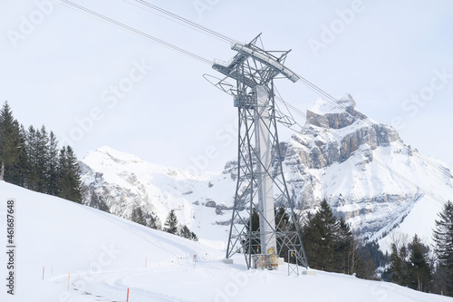 beautiful winter landscape with snowy mountains, Swiss Alps, snowfall in forest, iron construction for the funicular in Engelberg, dark green coniferous trees, sport and travel