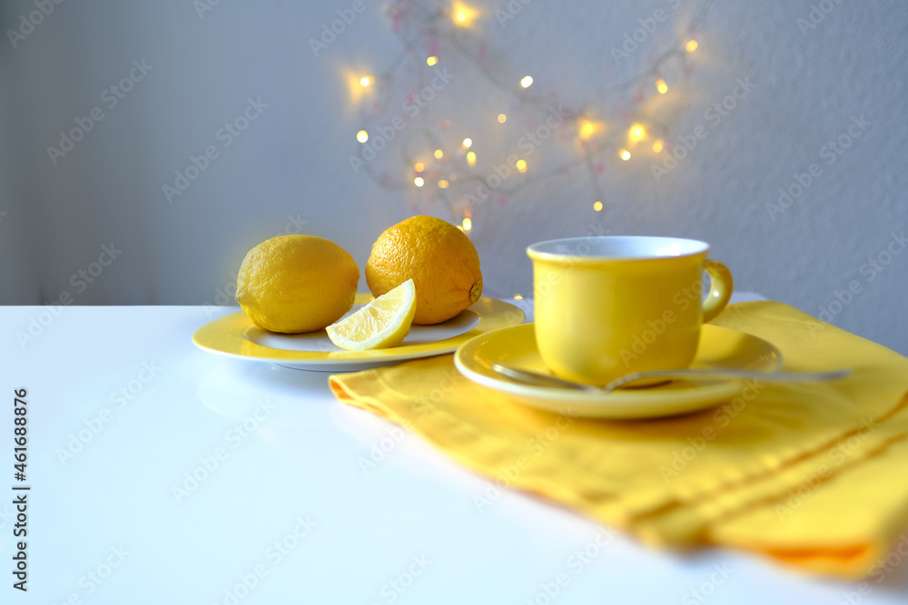 tea still life in yellow, fresh lemons on a plate, a cup of hot aromatic tea, linen napkin, garlands are shining, the concept of tea drinking at home, teatime, warm mood, sweet home tea still life in yellow, fresh lemons on a plate, a cup of hot aromatic tea, linen napkin, garlands are shining, the concept of tea drinking at home, teatime, warm mood, sweet home