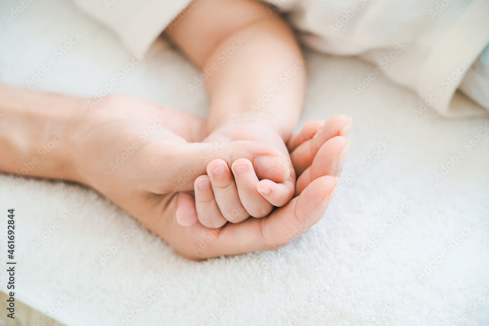 赤ちゃんの手を支えるお母さんの手