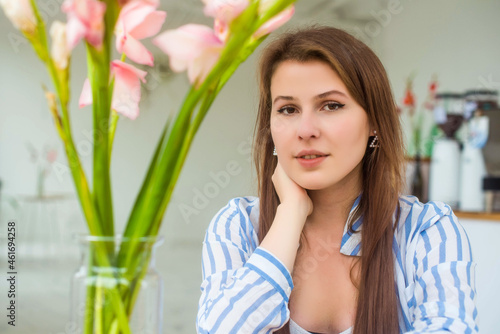 Portrait of young attractive caucasian woman looking at camera smiling with urban lifestyle concept at blurred cafe background with bokeh. feeling positive. Florist.