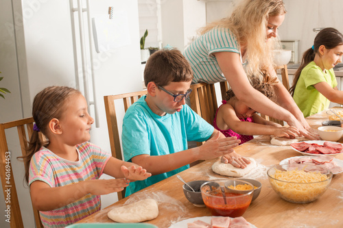 the teacher is learning children to cook pizza