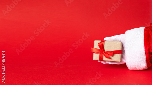 white gift box with red ribbon bow in santa hand on red background. © Inna