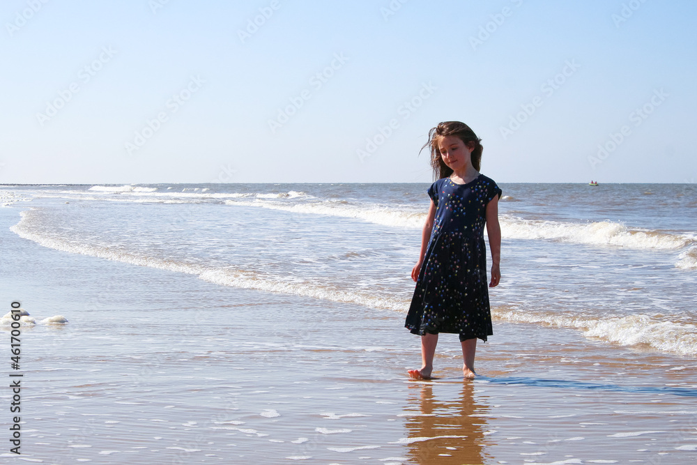 Young girl playing on. the Cromer beach in a sunny day of summer, joy, happiness, holiday, vacation in England, United Kingdom, Norfolk coast, North sea
