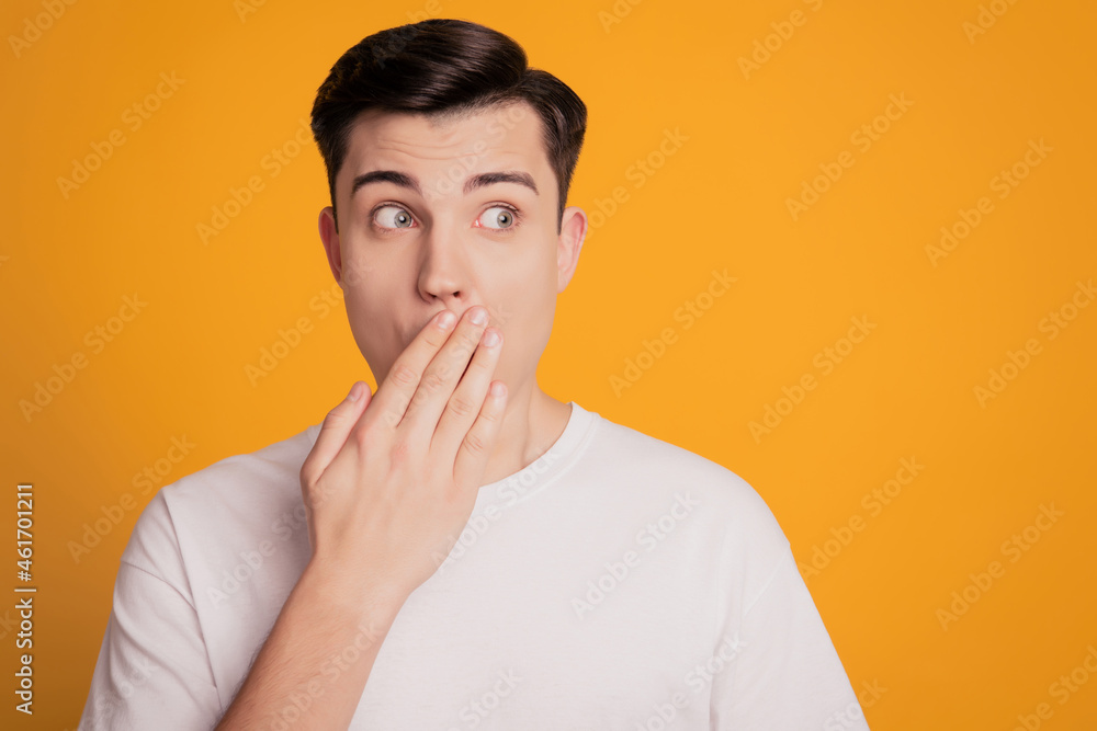 Portrait of scared man in white t-shirt cover mouth with hand look yellow empty space background Portrait of scared man in white t-shirt cover mouth with hand look yellow empty space background