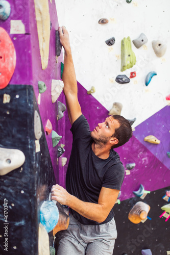 Sportsman climber climbing on artificial wall indoors. Extreme sports concept.