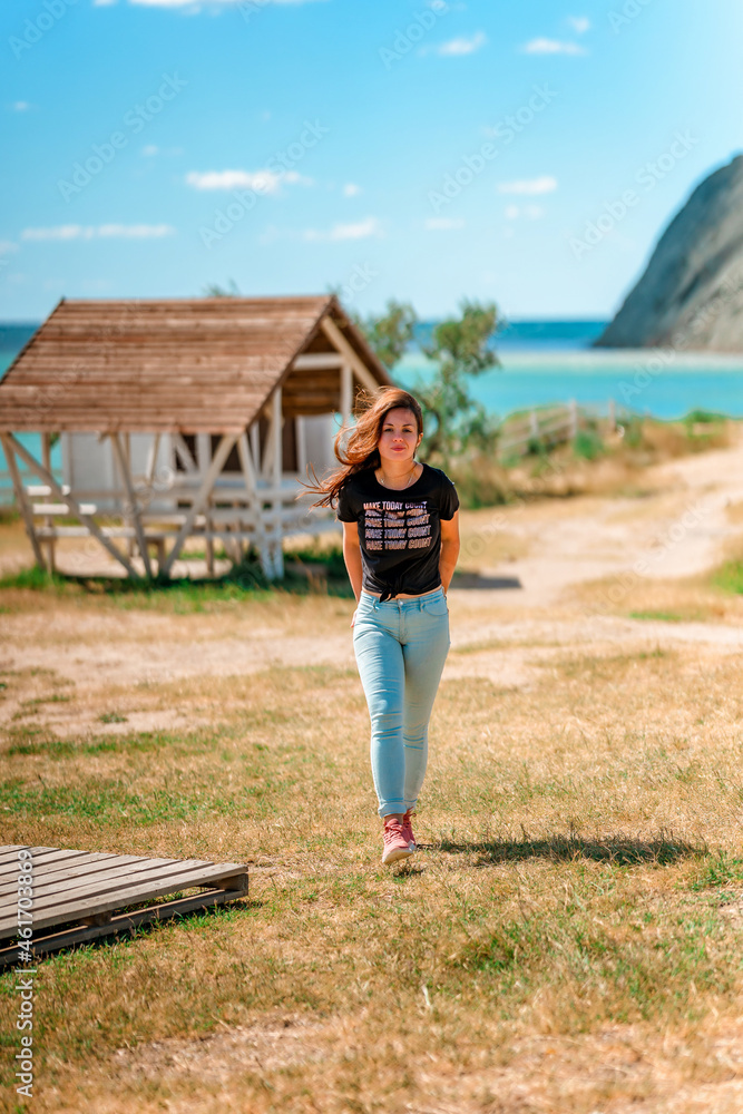 A beautiful young woman in a rustic-style area near and a mountain view of Cape Chameleon, Crimea