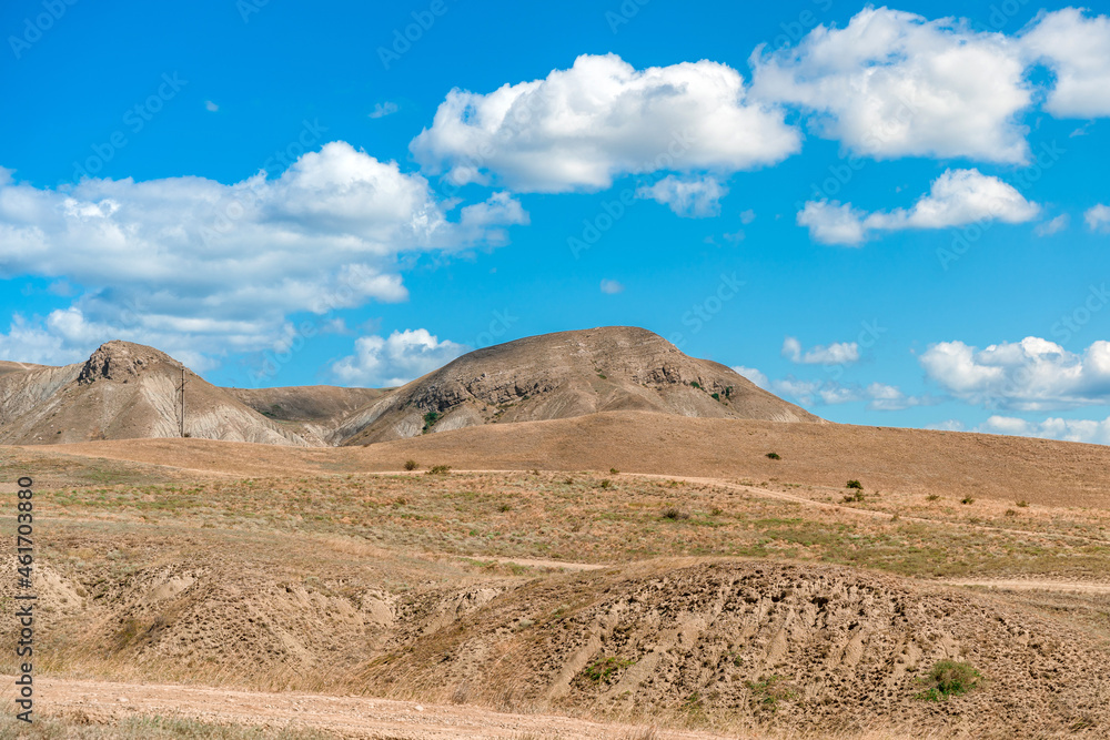 Beautiful landscape of mountainous terrain with hills against a blue sky with clouds Beautiful landscape of mountainous terrain with hills against a blue sky with clouds