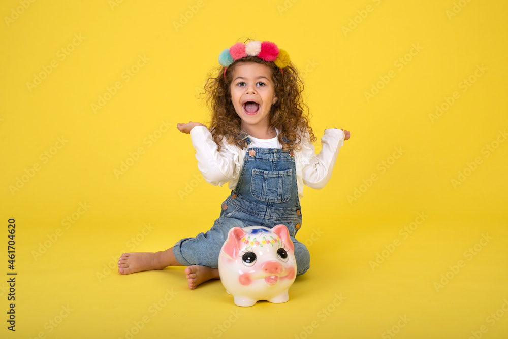 Happy Little Children girl saved a little money for future need wearing white T-shirt holding piggy bank, Saving money since childhood on yellow background studio shot with copy space Happy Little Children girl saved a little money for future need wearing white T-shirt holding piggy bank, Saving money since childhood on yellow background studio shot with copy space