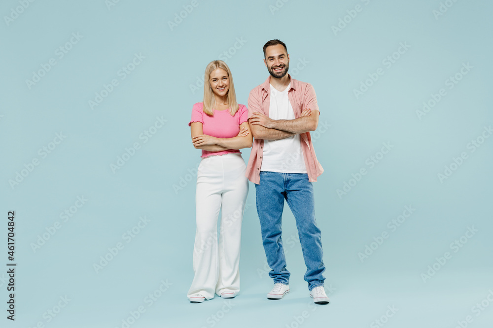Full body happy young smiling fun couple two friends family man woman in casual clothes stand back to back hold hands crossed together isolated on pastel plain light blue background studio portrait. Full body happy young smiling fun couple two friends family man woman in casual clothes stand back to back hold hands crossed together isolated on pastel plain light blue background studio portrait.