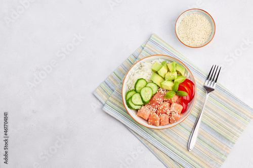 Traditional hawaiian ahi, a diet meal with fish. Poke bowl of salmon, rice, avocado, cucumber, pepper and sesame seeds. Top view. Copy space. 