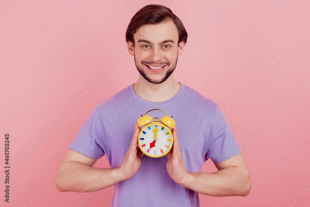Photo of young man happy positive smile hold clock alarm time timer isolated over pastel color background Photo of young man happy positive smile hold clock alarm time timer isolated over pastel color background