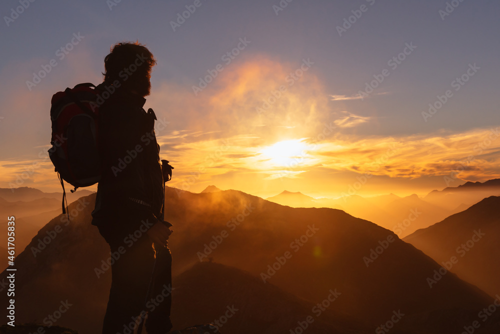 hiker watching the sunset from the top of a mountain at sunset. hiker watching the sunset from the top of a mountain at sunset.