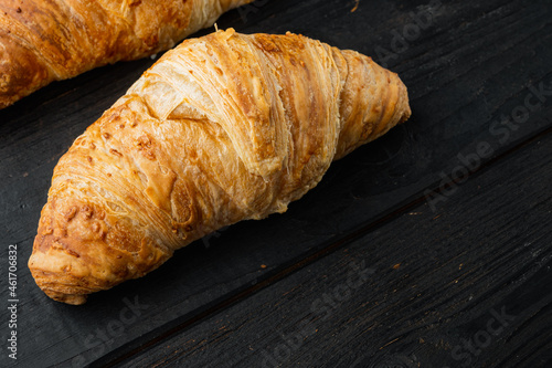 Crispy fresh croissants, on black wooden table background, with copy space for text