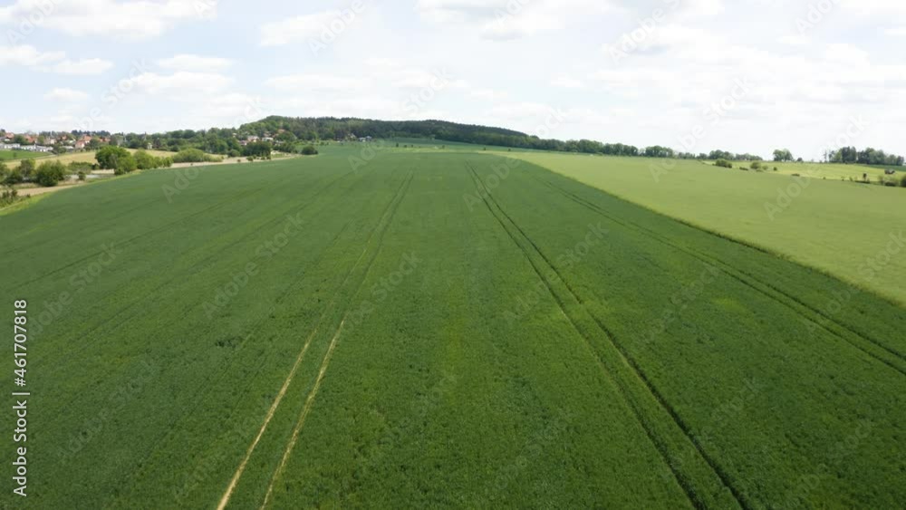Aerial drone shot - a green field in a rural area - drone flies backward Aerial drone shot - a green field in a rural area - drone flies backward