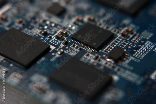 Circuit board close up of a turquoise board with black chips, narrow depth of field, blurry bokeh