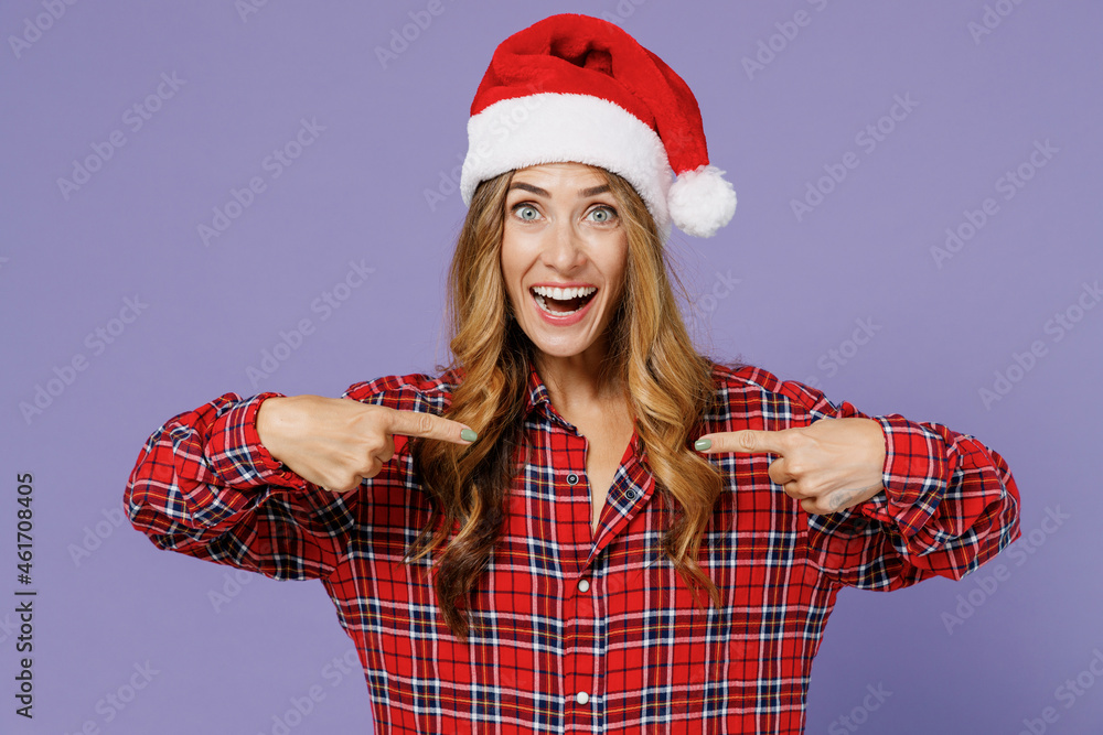 Merry happy young Santa woman 30s wears shirt Christmas hat pointing index fingers on workspace copy space mockup promo commercial areaisolated on plain pastel light violet background studio portrait. Merry happy young Santa woman 30s wears shirt Christmas hat pointing index fingers on workspace copy space mockup promo commercial areaisolated on plain pastel light violet background studio portrait.