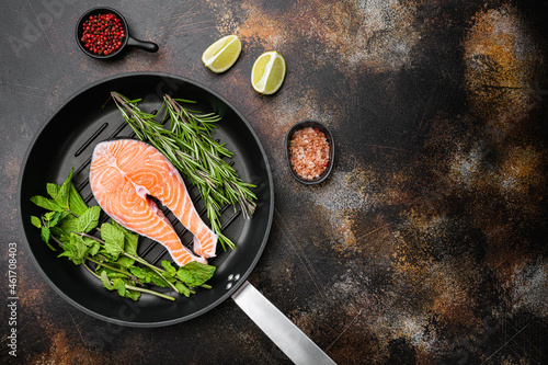 Fresh raw salmon steak, in cast iron frying pan , on old dark rustic table background, top view flat lay, with copy space for text