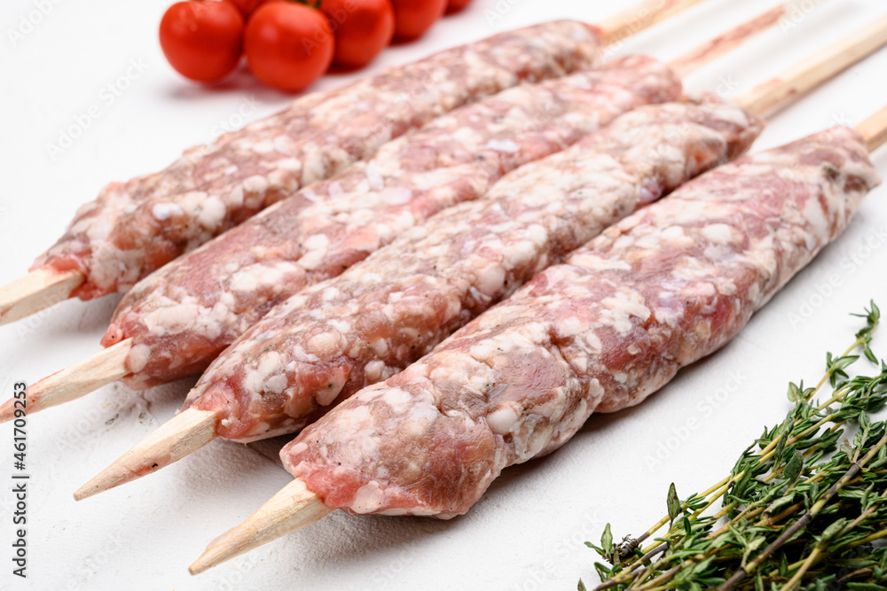 Raw lula kebab, lyulya-kebab minced meat, shish kebab ready to cook , with grill ingredients, on white stone table background