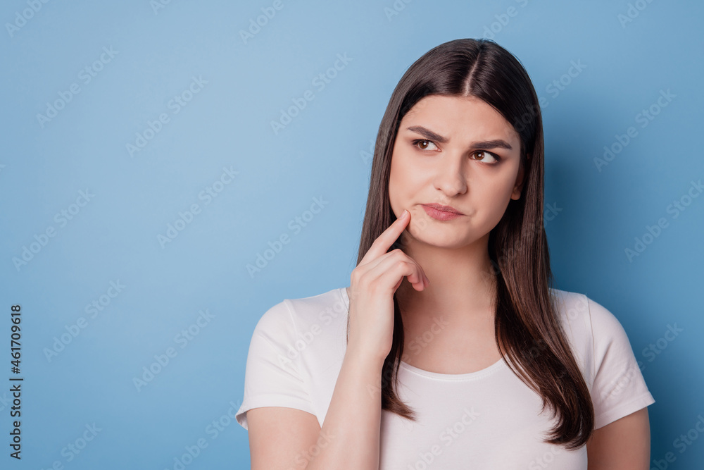 Portrait of pretty minded unsure lady look empty space finger cheek on blue background Portrait of pretty minded unsure lady look empty space finger cheek on blue background