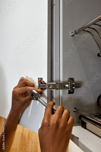 Female hands with spanner, fixing cupboard door