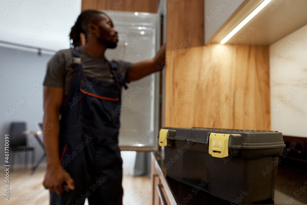 Service toolkit on kitchen surface, handyman on background, blured Service toolkit on kitchen surface, handyman on background, blured