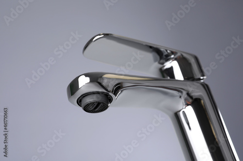 Single handle water tap on grey background, closeup