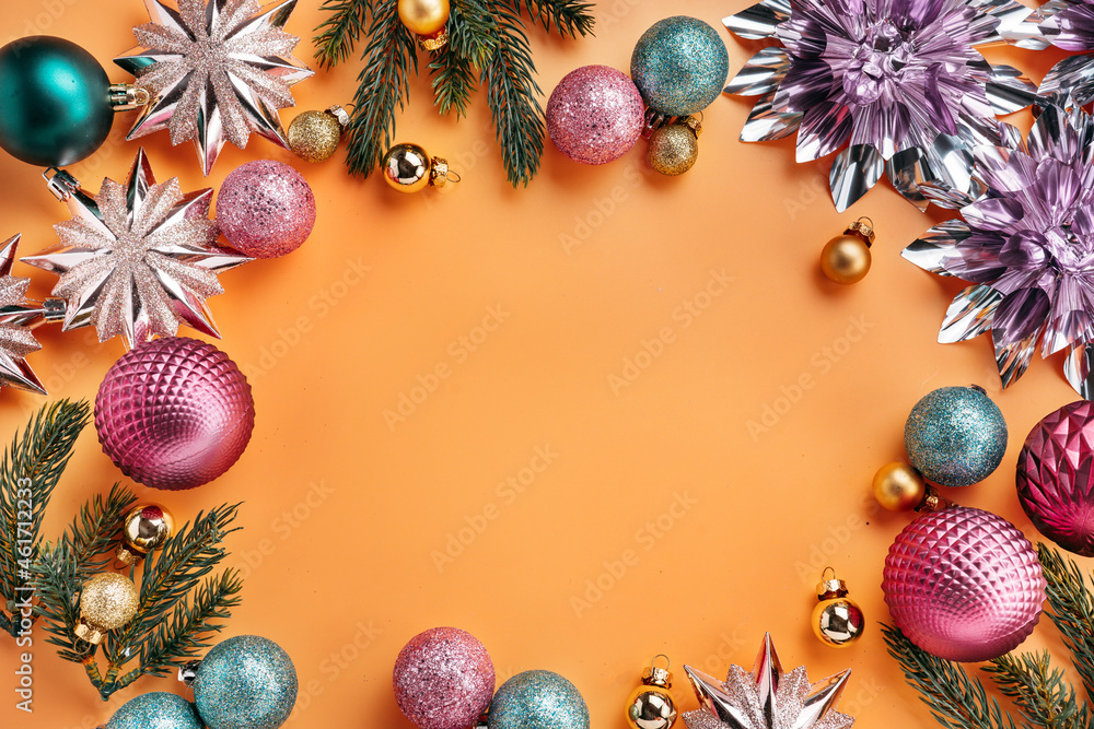 Overhead composition of Christmas background. Round frame made of shiny decorations on orange background with copy space Overhead composition of Christmas background. Round frame made of shiny decorations on orange background with copy space
