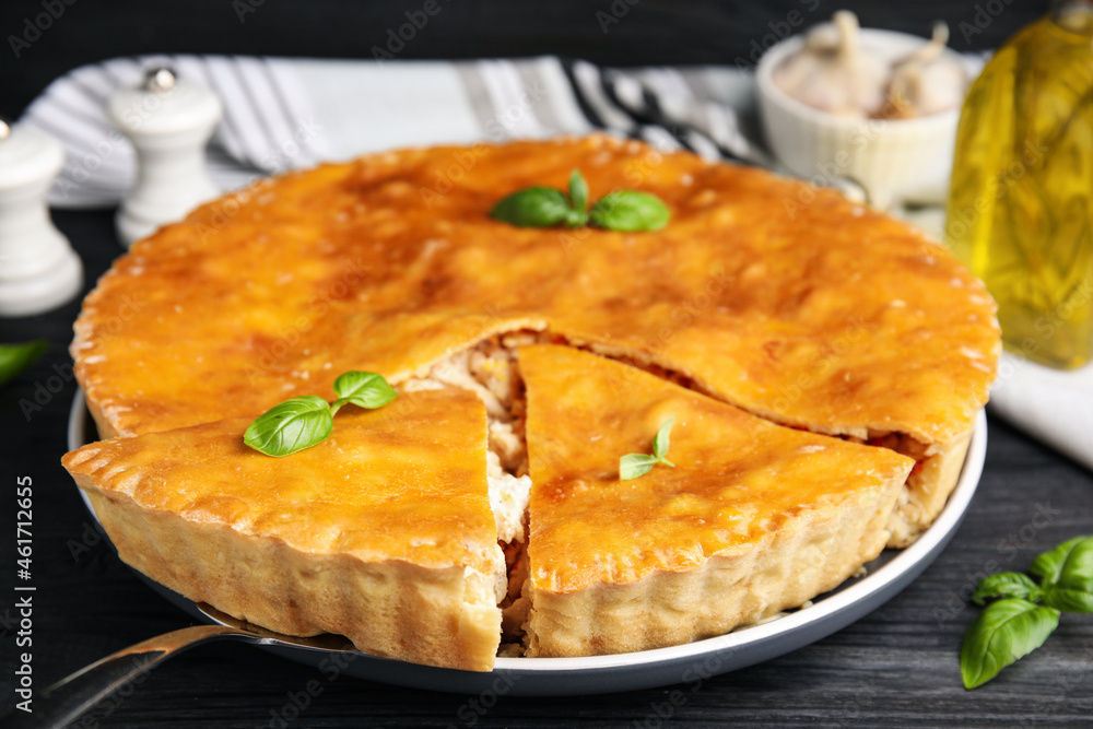 Delicious meat pie with basil on black table, closeup Delicious meat pie with basil on black table, closeup