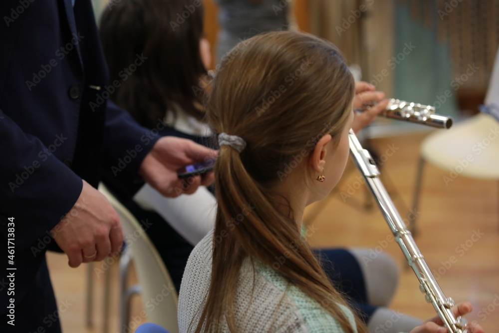 Group of college students of music faculty with musical instrument flute in class in classroom next to teacher holding phone.Concept of children's schooling and education