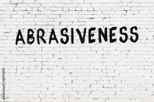 White wall with black paint inscription abrasiveness on it