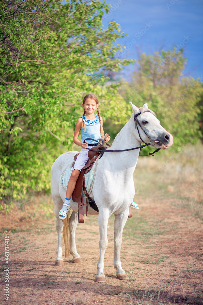 Schoolgirl girl rides a white pony. A child riding a horse