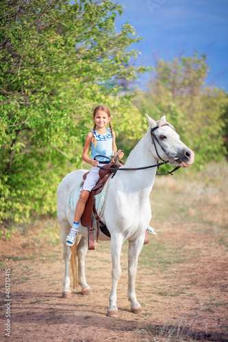 Schoolgirl girl rides a white pony. A child riding a horse