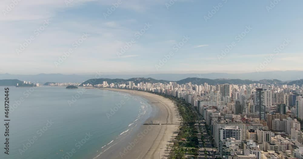 beautiful beach with city buildings on the shoreline. drone flying over buildings and shore. slow side camera movement with mountains in the background. Santos. Blue sky beautiful beach with city buildings on the shoreline. drone flying over buildings and shore. slow side camera movement with mountains in the background. Santos. Blue sky