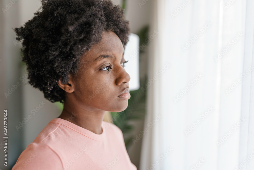 Fototapeta premium Pensive sad young African American woman look in window
