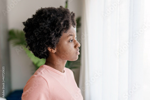 Pensive sad young African American woman look in window © Louis-Photo
